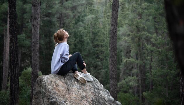 Frau sitzt auf felsen im Wald