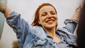 Frau, die sehr euphorisch die Arme hochwirft. 