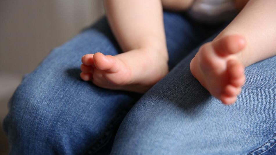 Baby sitzt auf dem Schoß einer Frau