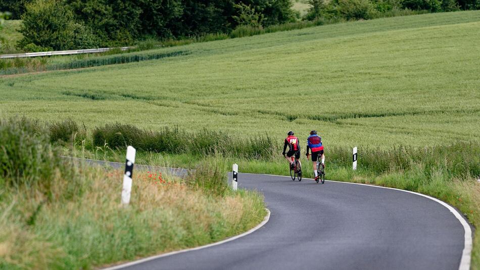 Zwei Radfahrer fahren auf einer Landstraße