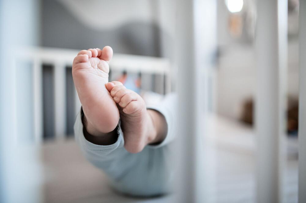 Ein Baby liegt in einem Beistellbett