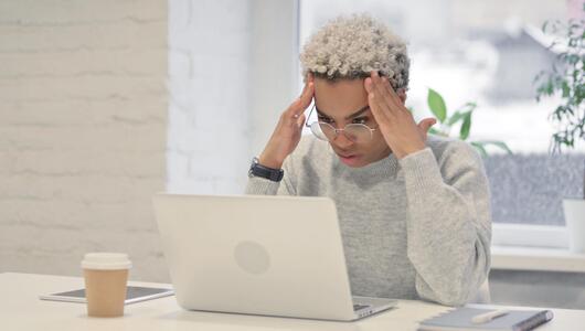 junge Frau sitzt fassungslos vor Computer