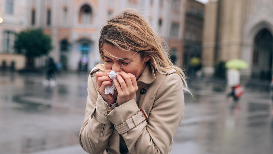 Heuschnupfen bei Regen - Frau schnäuzt sich im Regen