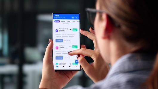 Frau nutzt Smartphone, um Stellenangebote zu durchsuchen
