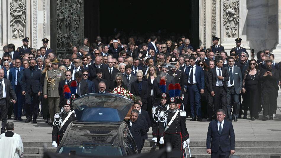 Trauergäste stehen vor einer Kirche.
