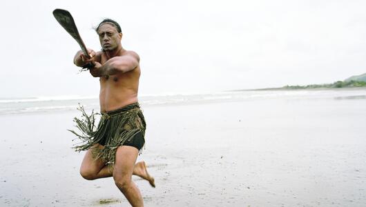 Maori-Mann performt Haka Powhiri am Strand
