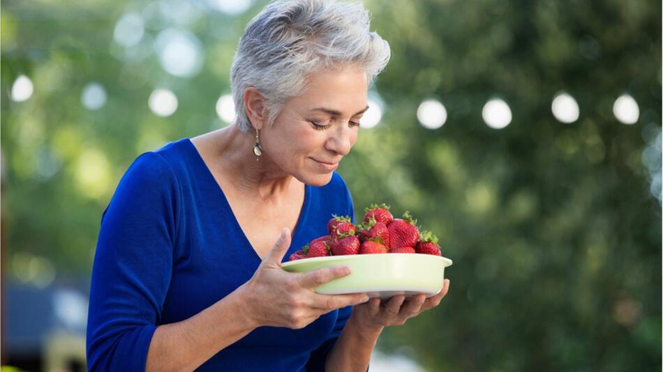 Frau hält eine Schale Erdbeeren.