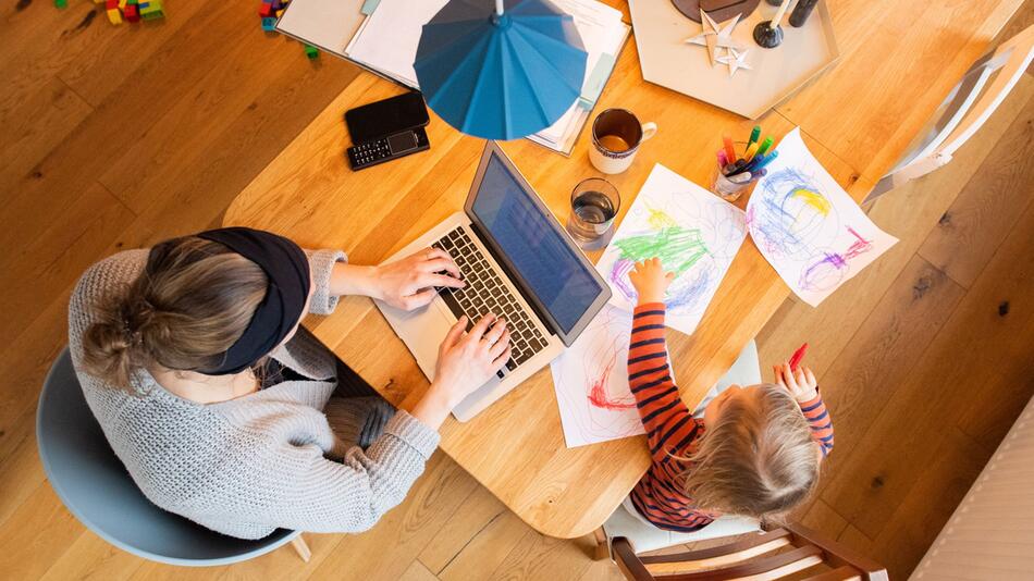 Eine Frau arbeitet im Homeoffice mit Kind