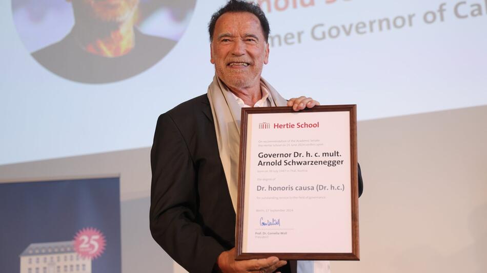 Arnold Schwarzenegger präsentiert stolz seinen Doktortitel in Berlin.