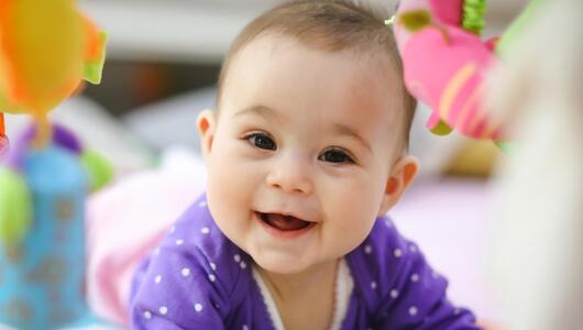 Niedliches lächelndes Baby schaut in die Kamera. 