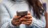 Eine junge Frau hält ein Smartphone in den Händen