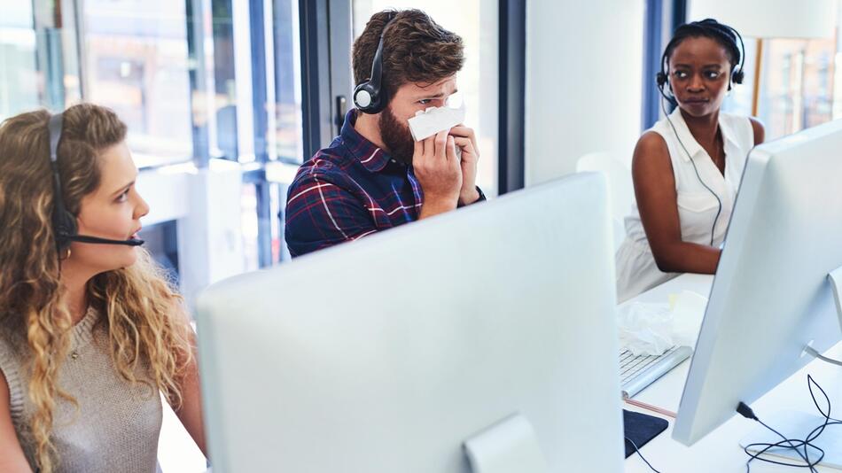 Mann sitzt krank im Büro