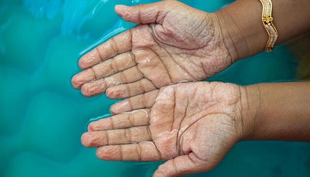 Schrumpelige Hände im Wasser