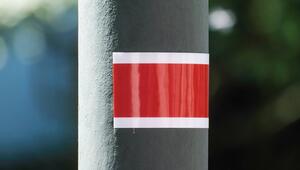 Ein Laternenring klebt an dem grauen Pfahl einer Laterne.