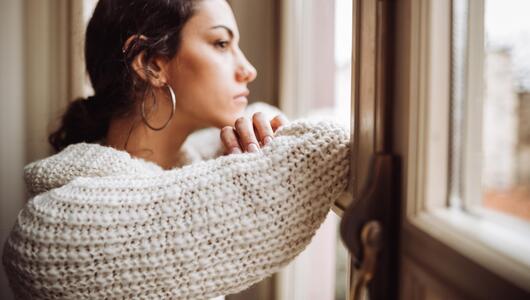 Junge Frau nachdenklich am Fenster