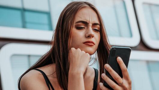 Frau blickt kritisch auf Smartphone