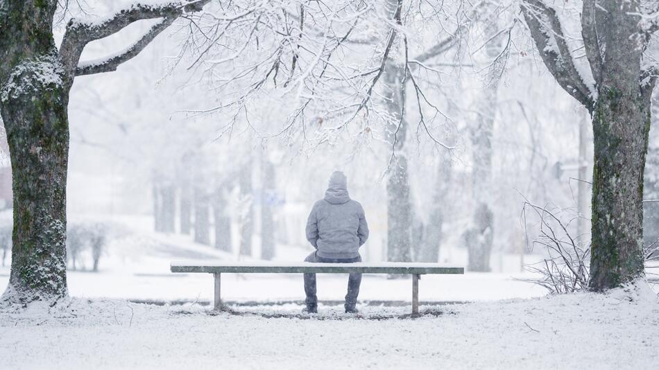 Mann sitzt im Schnee