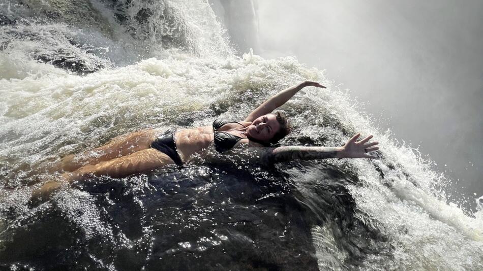 Eine Touristin badet am Rand der Victoria-Fälle in Simbabwe