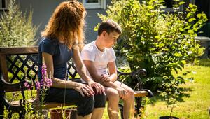 Mutter spricht mit ihrem Sohn auf einer Gartenbank