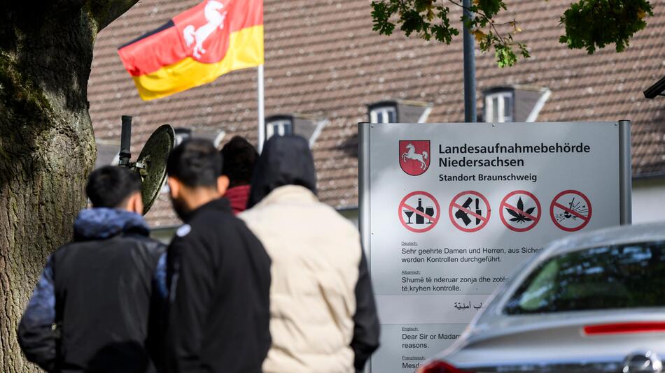 Drei Männer vor einem Schild der Landesaufnahmebehörde Niedersachsen