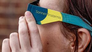 Frau mit Schutzbrille betrachtet eine partielle Sonnenfinsternis