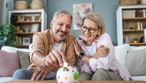Eine Renterin und ein Rentner werfen Münzgeld in ein Sparschwein.