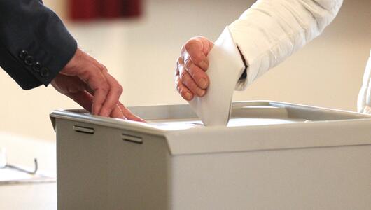 Eine Frau gibt ihre Stimme an einer Wahlurne ab.