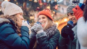 Lachende Weihnachtsmarktbesucher trinken Glückwein.