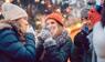 Lachende Weihnachtsmarktbesucher trinken Glückwein.