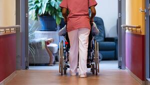 Eine Pflegekraft schiebt einen Pflegebedürftigen im Rollstuhl