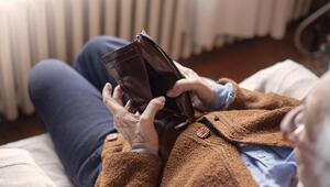 Ältere Person auf dem Sofa mit leerem Portemonnaie