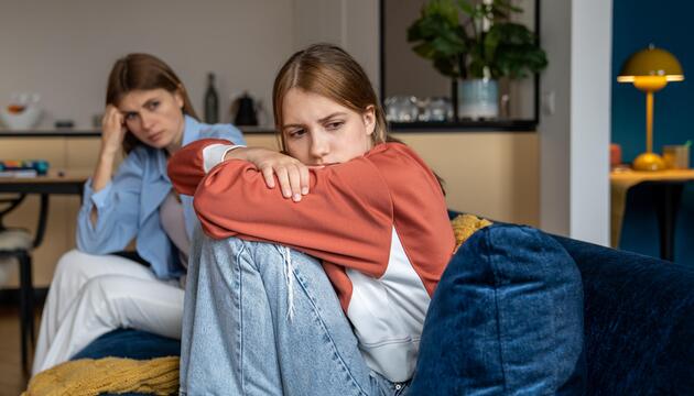 Frustriertes, beleidigtes Teenager-Mädchen sitzt neben der Mutter