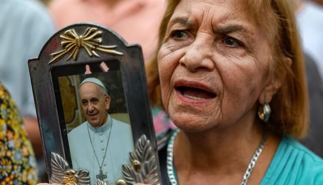 Frau betet mit Foto von Papst Franziskus in der Hand