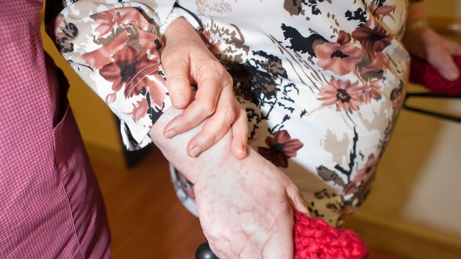 Frau hilft einer Seniorin am Rollator