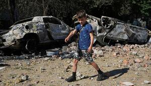 Ein Junge in der Ukraine zwischen zerstörten Autos