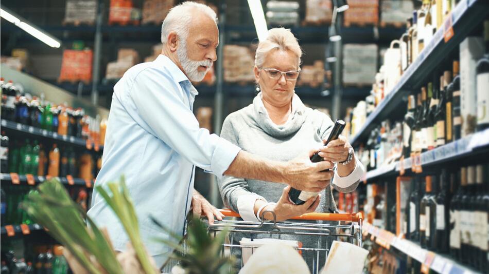 Älteres Paar im Supermarkt vergleicht Preise.