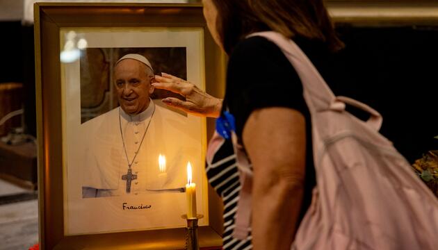 Eine Frau berührt ein Foto von Papst Franziskus.