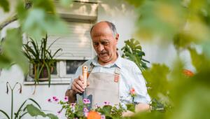 Älterer Mann, der sich um seine Topfpflanzen kümmert.