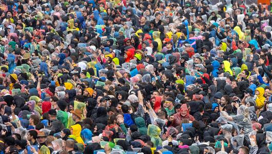 Festivalgäste in Regenkleidung stehen bei starkem Regen auf dem Gelände von Rock im Park in Nürnberg