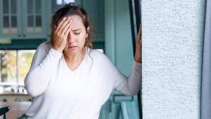 Junge Frau hält sich wegen Schwindel an der Wand fest