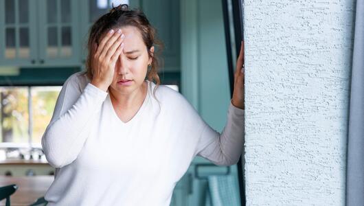 Junge Frau hält sich wegen Schwindel an der Wand fest