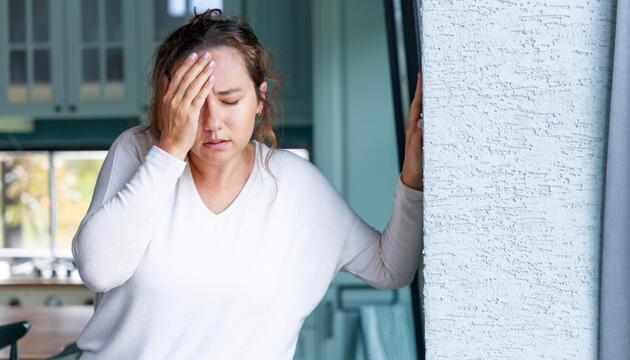 Junge Frau hält sich wegen Schwindel an der Wand fest