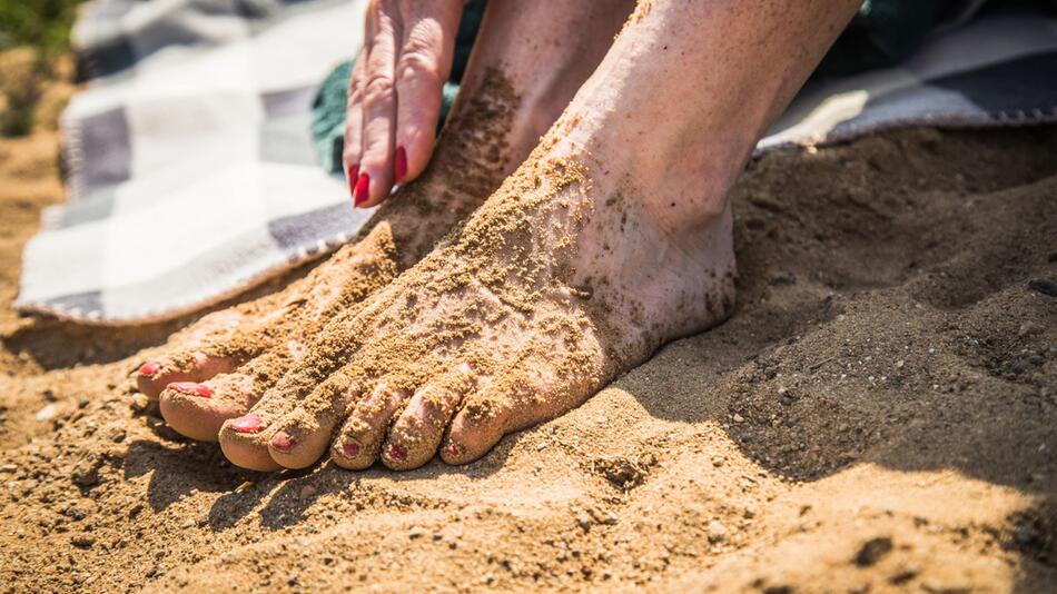 Sandige Frauenfüße am Badesee