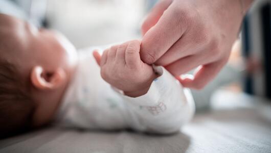 Baby hält die Hand der Mutter fest