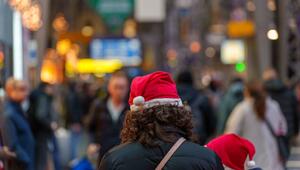 Eine Frau steht mit Weihnachtsmütze auf einem Bahnhof