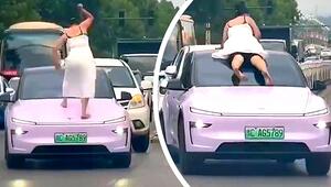 Frau klettert auf rosa Tesla und fährt auf Windschutzscheibe mit