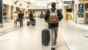 Junger Mann geht durch einen modernen Bahnhof, und zieht einen Koffer 