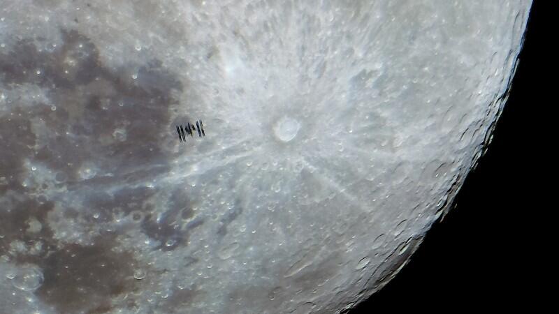 Die internationale Raumstation (ISS) fliegt vor dem Mond.