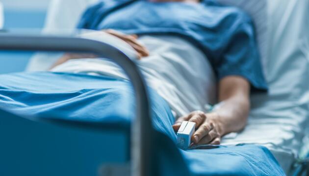 Patient in Krankenhausbett mit Pulsoximeter am Finger
