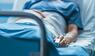 Patient in Krankenhausbett mit Pulsoximeter am Finger